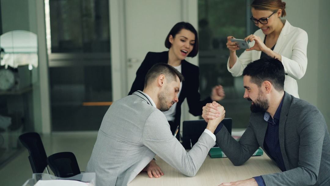 Two men arm wrestling with colleagues watching