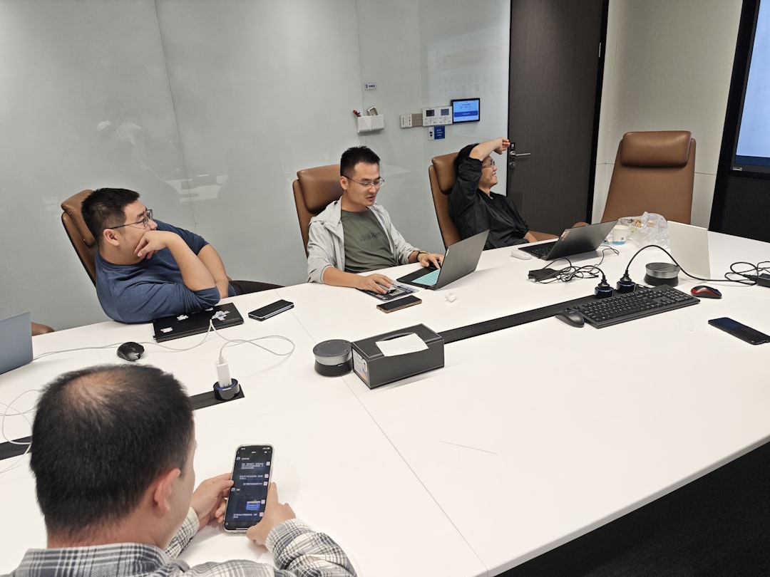 Four men in a meeting room with laptops.