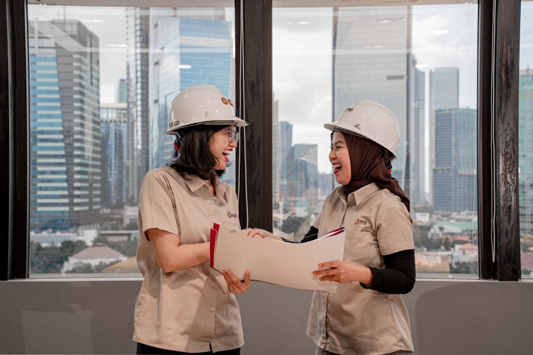 Two women in hard hats discussing blueprints